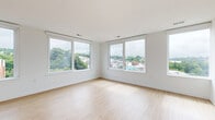 Located on the fifth floor at 4300 Ridge Ave in Philadelphia's East Falls neighborhood, this 2-bedroom, 2-bathroom unit offers a clean, contemporary aesthetic throughout. Light-toned hardwood flooring runs seamlessly across the entire space, complementing crisp white walls and modern finishes.

The open-concept kitchen and living area serves as the heart of the unit. The kitchen is outfitted with flat-front, light gray cabinetry extending to the ceiling for ample storage, stainless steel appliances including a refrigerator, range, and microwave, and a large center island with a white quartz countertop and integrated sink. Pendant lighting and large windows flood the space with natural light and frame elevated treetop views of the surrounding neighborhood.

Both bedrooms are well-proportioned and bright, featuring large windows that capture expansive outdoor views. The primary bedroom benefits from generous natural light and a sense of openness. Each room is finished with the same warm hardwood flooring found throughout the unit.

The two bathrooms reflect a modern design sensibility. The primary bathroom features a glass-enclosed walk-in shower, a floating wood vanity with a white countertop, and tile flooring. The second bathroom includes a full soaking tub with shower, clean white tile surround, and coordinating finishes, providing a functional and polished space.