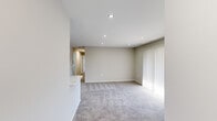 This single-floor, 2-bedroom, 1-bathroom residence offers a clean, modern aesthetic with neutral tones and quality finishes throughout. The open living room is carpeted and bathed in natural light from large sliding glass doors fitted with vertical blinds, providing access to an outdoor view. Recessed lighting throughout the space adds a bright, contemporary feel.

The kitchen features white shaker-style cabinetry with matte black hardware, quartz countertops with subtle veining, a subway tile backsplash, stainless steel appliances including a full-size refrigerator and dishwasher, and hardwood-style flooring — creating a crisp, functional workspace.

The primary bedroom is generously sized, offering two windows with horizontal blinds that invite ample natural light, plush carpeting, and recessed lighting. The second bedroom also features carpeted floors, recessed lighting, and a built-in closet with shelving. Two closets provide practical storage solutions throughout.

The bathroom is elegantly appointed with full marble-look tile surrounding the bathtub and shower, a quartz vanity countertop, a modern black-framed mirror, and hardwood-style flooring. A dedicated laundry room includes a full-size washer and dryer with overhead wire shelving for added convenience.