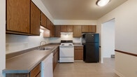 This single-floor, 2-bedroom, 1-bathroom unit in Saginaw, Michigan offers a practical and well-organized layout. The kitchen is equipped with warm wood-toned cabinetry providing ample storage, laminate tile flooring, and a full suite of appliances including a white electric range, black refrigerator, dishwasher, and a built-in range hood. Generous counter space and a double basin sink add to the kitchen's functionality.

The living area is spacious and carpeted, featuring sliding glass doors dressed with vertical blinds that allow natural light to fill the room while offering views of the surrounding greenery. A wall-mounted air conditioning unit and baseboard heating ensure year-round comfort.

Both bedrooms are carpeted and share a similar design, each featuring a ceiling fan with light fixture, a window with vertical blinds, and baseboard heating. Natural light flows freely through the windows, which overlook outdoor greenery.

The bathroom includes a full tub and shower combination with classic tile surround in a neutral tone, a vanity with storage, and wood-look flooring. The overall color palette throughout the unit is neutral and clean, creating a simple, livable ambiance throughout.