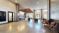 Located at 5176 Old Town Hall Rd in Eau Claire, Wisconsin, this expansive community amenity facility offers a thoughtfully designed, single-floor layout spanning a substantial footprint. The architectural style blends contemporary and industrial elements, with polished concrete floors, soaring ceilings, and large windows that flood interior spaces with natural light throughout.

The grand living area serves as a welcoming focal point, featuring double-height ceilings, a dramatic stone-accented fireplace with slatted wood paneling, a built-in floor-to-ceiling bookcase, and an open, airy lounge space. An adjacent lounge room offers comfortable seating and a large wall-mounted display, making it ideal for relaxation or community gatherings.

Two well-equipped fitness rooms provide ample space for cardio machines, strength equipment, and varied workout routines, enhanced by large windows overlooking the outdoor grounds and motivating graphic wall accents. The dedicated office, enclosed in glass, features a geometric accent wall, pendant lighting, and a serene outdoor view.

Two dining areas accommodate both intimate meetings and larger group gatherings, with one offering a private conference-style setup surrounded by expansive windows. A hallway with hexagonal tile flooring and built-in wood bench provides a functional transition space.

Outdoors, a resort-style pool with lounge chairs, shaded pergola seating areas, and open-air patios with communal dining and Adirondack seating create an inviting exterior environment set against the backdrop of a modern multi-story building.