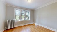 Located at 1002 North Boulevard in the historic village of Oak Park, Illinois, this 2-bedroom, 1-bathroom residence offers a thoughtfully arranged single-floor layout. Classic hardwood floors flow throughout every room, complemented by crisp white crown molding and clean baseboards that lend a timeless architectural character to the space.

The primary bedroom is generously proportioned, featuring a large multi-pane window that frames views of surrounding mature trees, allowing abundant natural light to fill the room. A classic cast-iron radiator adds a charming vintage touch. The second bedroom is equally bright, with its own window overlooking neighboring brick architecture.

Two hallways connect the rooms efficiently, with a dedicated closet providing practical storage. The kitchen is efficiently organized in a galley style, equipped with stainless steel appliances including a gas range, built-in microwave, and refrigerator, alongside rich wood cabinetry and granite-style countertops over hardwood flooring.

The bathroom features full stone-look tile work on both the floor and tub surround, a dark wood vanity, and a windowed tub-shower combination that adds brightness. The dining room rounds out the layout, completing a functional and cohesive living space with consistent neutral-toned walls throughout.