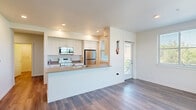 Located at 22199 NE Sandy Blvd in Fairview, Oregon, this thoughtfully designed 3-bedroom, 2-bathroom residence offers a clean, contemporary aesthetic throughout. The open-concept kitchen and living area serves as the heart of the home, featuring white shaker cabinetry, stainless steel appliances including a refrigerator, range, and over-the-range microwave, and a generous island with a quartz countertop and undermount sink — ideal for both meal preparation and casual dining. Wood-style plank flooring runs throughout, complementing the bright, neutral color palette and recessed lighting. A private balcony off the living area provides pleasant views of the landscaped surroundings and neighborhood greenery. The primary bedroom is a comfortable retreat, highlighted by a large window that invites abundant natural light and a spacious walk-in closet with built-in wire shelving. The two bathrooms are finished with white vanity cabinetry, quartz countertops, and wood-style flooring; the full bathroom includes a tub/shower combination with a curved rod. Two additional bedrooms offer well-proportioned spaces with ample closet storage. Hallways connect the rooms efficiently, contributing to a practical and functional floor plan suited for everyday living.