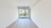 Located at 6085 Rue Sherbrooke Est in Montréal's Mercier-Hochelaga-Maisonneuve borough, this well-appointed one-bedroom, one-bathroom unit offers a thoughtfully designed layout with a clean, modern aesthetic throughout. Light wood laminate flooring flows continuously across every room, complementing the bright white walls and creating a cohesive, airy atmosphere.

The living room is the heart of the unit, anchored by a large sliding glass door that opens onto a private balcony with a metal railing. Lush tree canopy views bring a sense of greenery and tranquility directly into the space, filling the room with natural light.

The bedroom is a comfortable, well-proportioned retreat featuring a sliding closet with built-in storage and a dedicated window framing verdant outdoor views. A pendant light fixture adds a subtle modern touch to the room.

The bathroom is finished with neutral large-format floor tiles and features a floating wood-toned vanity with a white countertop, a framed mirror, and a clean, minimalist layout that makes efficient use of the space.

Throughout the unit, the design emphasizes clean lines, neutral tones, and natural materials, resulting in a calm and functional living environment suited to modern urban living in Montréal.