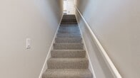 Located at 930 Terrapin Ln, Unit 204, this 2-bedroom, 2-bathroom residence spans 1,150 square feet across two floors. The ground floor hosts a private, automated single-car garage with a dedicated entry staircase leading up to the main living level. The expansive upper floor encompasses 1,070 square feet and features an open-concept kitchen and living room anchored by vaulted ceilings and light hardwood-style flooring. The kitchen is appointed with two-tone cabinetry — white upper cabinets and gray lower cabinets — complemented by white quartz countertops, stainless steel appliances, a matte black faucet, and an in-unit stacked washer and dryer. The living room opens to a private balcony through sliding glass doors, filling the space with natural light. Both bedrooms are carpeted and include ceiling fans, windows with blinds, and dedicated closets; the primary bedroom measures 190 square feet and features a spacious walk-in closet with wire shelving. The two bathrooms include hardwood-style flooring, gray vanities, and a sleek glass-enclosed shower with matte black fixtures. The unit's neutral color palette and clean architectural lines create a bright, modern ambiance throughout.