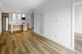 Located at 151 Mill St in Toronto's vibrant Distillery District neighbourhood, this thoughtfully designed one-bedroom, one-bathroom unit offers a clean, modern aesthetic across a single floor. Light hardwood flooring flows continuously throughout, lending warmth and cohesion to the space.

The open-concept kitchen serves as the heart of the unit, showcasing a striking two-tone design with white upper cabinetry and natural wood-grain lower cabinets. A white quartz countertop extends across the full run, complemented by a glass backsplash and a gold-toned undermount sink. Stainless steel appliances — including a built-in microwave, electric range, and full-size refrigerator — complete the modern kitchen package. A large island with a waterfall-edge countertop and under-lighting provides additional workspace and defines the living area.

The bedroom is a calm, minimalist retreat finished in crisp white tones, featuring recessed lighting and dual sliding-door closets with built-in hanging rods for generous storage.

The bathroom is finished with large-format stone-look wall tiles, a soaker tub with an integrated shower and adjustable sliding rail, and wood-accented cabinetry for a spa-like feel. A hallway connects the rooms efficiently, completing this well-appointed urban residence.