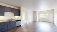 Located at 470 Alexander Loop in Eugene, Oregon, this two-bedroom, two-bathroom apartment offers a well-designed single-level layout. The open-concept kitchen and living area serves as the heart of the unit, featuring rich dark wood-style cabinetry, stainless steel appliances including a refrigerator, range, microwave, and dishwasher, and light countertops. Wood-style flooring runs through the kitchen and living areas, adding warmth and continuity to the space. The living room is bright and airy, with large windows and a sliding glass door that opens onto a private balcony overlooking the landscaped community grounds and surrounding building exterior. Both bedrooms are comfortably sized, with plush carpeting and built-in closets with bifold doors for ample storage. The primary bedroom offers a generous footprint and direct access to its own bathroom. Each bathroom is clean and functional, featuring a full tub-shower combination, with one bath showcasing a dark wood vanity, integrated sink, and a large mirror. The unit's neutral color palette of soft creams and whites creates a calm, move-in-ready atmosphere throughout.