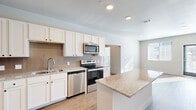 Located at 2580 Cahill Pond Vw in Colorado Springs, CO, this single-floor residence offers four bedrooms and four bathrooms within a thoughtfully designed layout. The kitchen serves as a central highlight, showcasing white shaker cabinetry, granite countertops, a tile backsplash, a central island, and a full suite of stainless steel appliances including a range, microwave, dishwasher, and refrigerator. Light wood-style flooring runs throughout the main living and kitchen areas, lending warmth and continuity to the open-concept space. The living room receives generous natural light through large windows fitted with blinds, and features a recessed lighting and a welcoming entry door. Each bedroom is carpeted and outfitted with a ceiling fan, with the primary bedroom benefiting from dual windows that invite abundant sunlight. The walk-in closet provides wire shelving for practical storage. The bathrooms are finished with large-format tile surrounds in the tub-shower combinations, granite-topped vanities, and wood-look flooring. Clean, neutral tones and modern finishes are carried consistently throughout the home, creating a cohesive and move-in ready environment.
