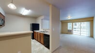 Located at 15913 East 4th Avenue in Spokane Valley, Washington, this second-floor unit offers a thoughtfully designed, single-level layout with a comfortable and functional floor plan. The open living area is finished with plush wall-to-wall carpeting and features a sliding glass door that opens onto a private balcony, providing natural light and outdoor views of the surrounding neighborhood. A wall-mounted heating and cooling unit ensures year-round comfort. The kitchen is positioned adjacent to the living space and features warm wood cabinetry, light countertops, tile flooring, and black appliances including a refrigerator, range, microwave, and dishwasher. A pass-through counter connects the kitchen to the main living area, enhancing the open feel of the space. Two bedrooms, each carpeted and bathed in natural light from large windows, offer restful and private retreats. The unit includes two full bathrooms, each appointed with a tub-shower combination, tile flooring, wood vanity cabinetry, and neutral wall tones. Throughout the unit, the warm beige and cream color palette creates a cohesive and inviting ambiance suited to a variety of interior styles.