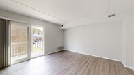 Located at 532 W Brookhaven Rd in Brookhaven, PA, this freshly renovated 2-bedroom unit offers a clean, modern aesthetic across a single floor. The interior has been thoughtfully updated with light-toned luxury vinyl plank flooring throughout, neutral gray walls, and bright white trim, creating a cohesive and contemporary feel.

The living area is generously proportioned, filled with natural light from a sliding glass door that opens onto a private balcony. The balcony overlooks a landscaped courtyard with views of the surrounding brick building exterior and greenery. A wall-mounted HVAC vent provides efficient climate control within the space.

Both bedrooms are well-sized and feature their own closets with bifold doors. One bedroom includes a built-in shelving unit within the closet, while the other benefits from a bright window that allows additional natural light. The layout connects the bedrooms conveniently to a stainless steel appliance kitchen visible through the hallway.

The bathroom has been fully renovated with a rich wood-toned vanity, a white integrated sink, brushed nickel fixtures, a large framed mirror, and light tile flooring, complemented by a full soaking tub and shower combination.

The entry area features a six-panel door and open sightlines into the main living space, reinforcing the unit's open and airy character throughout.