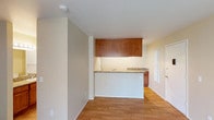 Located at 532 Broadway, Unit #215 in El Cajon, this single-floor residence offers a practical and well-appointed layout throughout. The open living area is finished with warm hardwood-style flooring, clean white walls, and neutral tones that create a bright, welcoming atmosphere.

The kitchen is defined by a peninsula-style pass-through counter topped with granite, providing both workspace and a natural divider between the kitchen and living area. Rich medium-toned wood cabinetry extends overhead, offering generous storage, while additional lower cabinetry and a refrigerator complete the kitchen's functional footprint.

The bedroom is carpeted for comfort and features a ceiling fan with light fixture, a mirrored sliding-door closet, and a wall-mounted HVAC unit. A sliding glass door floods the room with natural light and opens to a private patio area with views of the surrounding landscape.

The bathroom is well-equipped with a granite-topped vanity, a large wall mirror with Hollywood-style lighting, a soaking tub, and a separate shower/tub combination with a curtain rod. Built-in shelving in the bathroom area adds practical storage.

Overall, the unit presents a cohesive design with consistent granite and wood finishes throughout, offering a comfortable and functional living environment in El Cajon.