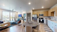 Located at 550 Marina Gateway Dr in Sparks, NV, this 2-bedroom, 2-bathroom residence offers a thoughtfully designed single-level layout with modern finishes throughout. The open-concept kitchen, dining, and living area creates a seamless flow, anchored by light wood-tone cabinetry, crisp white lower cabinets, a tile backsplash, and a full suite of stainless steel appliances including a refrigerator, range, microwave, and dishwasher. The dining area comfortably accommodates a round table, while the living room impresses with a bold geometric accent wall, ceiling fan, recessed lighting, and sliding glass doors that open to a private outdoor space. The primary bedroom features plush carpet, a large window with outdoor views, and a dedicated closet. The second bedroom makes a striking statement with a deep teal accent wall and soft carpet underfoot. Both bathrooms are finished with warm wood vanities, light countertops, and wood-look flooring — one includes a walk-in shower with glass doors, and the other a soaking tub and adjacent walk-in closet. A dedicated laundry area and two closets round out the functional amenities of this well-appointed residence.