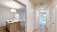 Located at 230 E 30th St in Kansas City, MO, this well-appointed 3-bedroom, 2-bathroom single-floor home offers a thoughtfully designed layout with modern finishes throughout. The open-concept kitchen and living area serves as the heart of the home, featuring light wood-toned cabinetry that extends to the ceiling, a large center island with a white quartz countertop and undermount sink, stainless steel appliances, and a stylish pendant light — all complemented by light hardwood flooring. The spacious living room is bathed in natural light through large windows and includes direct outdoor access via a glass-panel door. The generously sized primary bedroom features plush carpeting, a tray ceiling with ceiling fan, and a window for added brightness. Additional bedrooms are well-proportioned and carpeted. The primary bathroom is finished with warm wood vanity cabinetry, a white quartz countertop, and a glass-enclosed walk-in shower with marble-style tile surround. The second bathroom offers a soaking tub with a matching marble-tile surround. A dedicated in-unit laundry room with side-by-side washer and dryer adds everyday convenience. Two hallways connect the layout efficiently, completing this clean and contemporary home.
