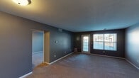 Located at 2104 E Wyndham Hill Dr NE in Grand Rapids, Michigan, this single-floor home offers a practical and comfortable layout throughout. The living room is a spacious, carpeted area finished with deep gray accent walls and features a glass-paneled entry door alongside a large window that draws in natural light and provides outdoor views. A pass-through counter seamlessly connects the living area to the kitchen, which is equipped with warm oak cabinetry, granite-style countertops, a gas range, black refrigerator, and hardwood-style flooring — making it both functional and visually cohesive. The bedrooms are generously sized with plush carpet, neutral-toned walls, and windows with blinds that offer exterior views. One bedroom notably includes multiple closets, providing excellent storage capacity. The bathroom is well-appointed with a wide vanity countertop, warm wood cabinetry, a large mirror with overhead lighting, hardwood-style flooring, and a combined tub and shower. Throughout the home, clean white trim and consistent neutral tones create a unified, move-in-ready aesthetic. The single-floor design ensures easy accessibility and seamless flow between all areas of the home.