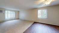 Located at 2210 Skillman Ave E in North St. Paul, Minnesota, this single-floor unit offers four bedrooms and one bathroom within a thoughtfully arranged floor plan. The layout is connected by two hallways that provide smooth circulation throughout the space.

The galley-style kitchen is equipped with white cabinetry featuring wood trim accents, a double-basin sink, coil-burner range, refrigerator, and overhead microwave. Rich wood-tone laminate flooring runs through the kitchen and extends into the adjacent living and dining area, which benefits from multiple windows fitted with vertical blinds and a ceiling fan overhead.

Each of the four bedrooms features plush carpeting, neutral walls, and windows dressed with vertical blinds that bring in natural light and views of surrounding greenery. Several bedrooms include ceiling fans for added comfort, and baseboard heaters are present throughout for efficient heating during colder months.

The full bathroom includes a tub-shower combination, a single-sink vanity with wood cabinetry, a wall mirror, and tile flooring. A linen closet is accessible directly from the bathroom entry. Storage is also available via a walk-in closet visible from the kitchen area. The overall aesthetic is clean and functional, with a neutral color palette maintained throughout.