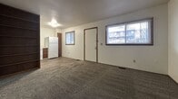 This 560 square foot apartment in Bloomington, IN, offers a practical living space with two bedrooms and one bathroom. The single-floor layout maximizes efficiency, with the primary bedroom being notably spacious at 390 square feet. The interior showcases a neutral color palette with white walls and grey carpeting throughout most rooms, creating a cohesive look. Windows in the bedrooms provide natural light and views of the surrounding area. The bathroom features a full-size bathtub with shower, white tiled walls, and essential fixtures. The main living area includes space for a refrigerator, indicating an open-concept design that likely combines the living room and kitchen. Wood-tone doors and trim add warmth to the space. The apartment's compact size and straightforward design make it an ideal choice for those seeking a low-maintenance living situation in a convenient location.