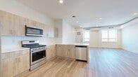 Located at 55 Washington St in East Orange, NJ, this well-appointed 2-bedroom, 2-bathroom residence offers a thoughtfully designed single-level layout. Light wood-tone flooring runs continuously throughout, creating a cohesive and airy feel across the entire space.

The open-concept kitchen and living area serves as the heart of the home. The kitchen features light wood cabinetry, crisp white countertops, and a full suite of stainless steel appliances including a gas range, built-in microwave, dishwasher, and refrigerator. A peninsula with pendant lighting defines the kitchen space while maintaining a seamless flow into the bright living area, which benefits from large windows that invite natural light.

The generously sized primary bedroom includes a dedicated closet and windows overlooking the surrounding neighborhood. The second bedroom is equally well-lit, with dual windows providing ample natural light and outdoor views. Both rooms feature clean white walls and the same warm wood flooring found throughout.

The bathrooms are finished to a modern standard. One bathroom showcases a frameless glass corner shower with marble-style tile surround, matte black fixtures, a white floating vanity, and large-format floor tiles. The layout also includes a closet for additional storage. The overall aesthetic is clean, contemporary, and move-in ready.