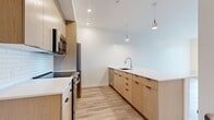 Located at 1630 SE Rural Street in Portland, OR 97202, this modern 1-bedroom, 1-bathroom apartment spans 510 square feet across a single floor. The open-concept living and kitchen area is anchored by light wood-style flooring that flows consistently throughout the unit, creating a cohesive and airy feel. Large floor-to-ceiling windows flood the living space with abundant natural light while offering views of the surrounding Portland neighborhood.

The kitchen features light wood cabinetry, stainless steel appliances including a electric range, over-the-range microwave, and refrigerator, complemented by a white subway tile backsplash and a breakfast bar peninsula. In-unit stacked washer and dryer provide added convenience.

The 100-square-foot bedroom includes a sliding-door closet and large windows that continue the unit's bright aesthetic. The bathroom is finished with a light wood vanity, white countertop, a full tub/shower combination, and wood-look tile flooring. Clean white walls and modern fixtures throughout lend the unit a contemporary, move-in-ready appeal suitable for those seeking efficient, well-appointed urban living.