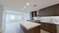 This well-appointed one-bedroom, one-bathroom unit offers a thoughtfully designed open-concept layout with modern finishes throughout. The combined kitchen and living area serves as the heart of the space, showcasing light wide-plank hardwood flooring, recessed lighting, and a seamless flow ideal for both daily living and entertaining.

The kitchen is a standout feature, equipped with rich dark walnut cabinetry extending to the ceiling, a striking marble-style backsplash, white quartz countertops, and a generously sized center island. Stainless steel appliances, including a gas range, dishwasher, and refrigerator, are complemented by a built-in wine cooler and glass display shelving, adding a refined touch.

The bedroom offers carpeted flooring, a ceiling fan, and a large picture window framing expansive city skyline views, flooding the room with natural light. A dedicated walk-in closet with double hanging rods provides ample storage.

The bathroom features full marble-style tile walls and flooring, a frameless glass walk-in shower with built-in niches and a mosaic tile floor, and a floating vanity with clean, minimalist hardware. A hallway connects the rooms efficiently, completing this well-organized and elegantly finished space.