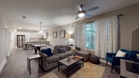 Located at 2810 University Square Drive in Tampa, Florida, this single-story residence offers a well-designed layout with a blend of modern finishes and functional living spaces. The kitchen is a standout feature, equipped with stainless steel appliances including a refrigerator, range, and microwave, complemented by a two-tone cabinetry scheme of white upper cabinets and dark lower cabinets. Light quartz countertops extend to a peninsula with a single-basin sink, providing additional prep and dining space. Wood-look plank flooring flows throughout the main living areas, adding warmth and continuity. The open living room offers generous space with a ceiling fan, large windows that invite natural light and outdoor greenery views, and enough room for a pool table alongside traditional seating arrangements. Bedrooms feature plush carpet flooring, natural light from windows, and dedicated closets with built-in shelving. One bedroom includes its own private entry door. The bathroom is finished with wood-look tile flooring, a dark vanity with white countertop, and a full tub-shower combination. A separate laundry room with a full-size washer provides added convenience. Recessed lighting throughout contributes to a clean, contemporary ambiance.
