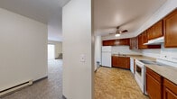 Located at 1434 Lakeview Dr in Darien, Illinois, this single-floor unit offers a practical and comfortable layout designed for everyday living. The kitchen is a functional centerpiece, featuring warm-toned wooden cabinetry that extends to the upper and lower walls, light-colored countertops, and durable tile flooring. White appliances — including a refrigerator, electric range, dishwasher, and a ceiling fan with light fixture overhead — complete the space efficiently. An open sightline connects the kitchen to the carpeted living area, which is bright and welcoming, anchored by a sliding glass door dressed with vertical blinds that allows natural light to filter in and provides access to the outdoors. The bedrooms are carpeted and neutrally finished, offering a calm atmosphere. One bedroom features dual bi-fold closet doors, providing generous storage capacity, while another bedroom benefits from a window with natural views of the surrounding greenery. The bathroom is clean and straightforward, appointed with a full-sized soaking tub and shower combo with a smooth surround. Throughout the unit, neutral wall tones, dark baseboards, and consistent carpeting in the living spaces create a cohesive, move-in-ready environment.