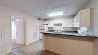 Located at 4811 Butler Rd in Little Rock, AR, this one-bedroom, one-bathroom unit offers a functional and efficient single-floor layout. The open-concept kitchen is a central feature, equipped with ample white cabinetry, dark laminate countertops, a stainless steel double sink, a white electric range, and a full-size refrigerator. A peninsula counter separates the kitchen from the combined dining and living area, creating a natural flow between spaces. The living and dining area features wood-look laminate flooring and is brightened by overhead fluorescent lighting, with a door providing access to the exterior and allowing natural light into the space. The bedroom is a quiet, carpeted retreat with neutral-toned walls and offers comfortable proportions. A dedicated closet provides convenient storage. The bathroom includes a full-size tub and shower combination with clean white surround walls and standard fixtures. Throughout the unit, a consistent neutral color palette of warm beige and white creates a cohesive and understated aesthetic. The layout is practical and well-organized, making efficient use of the available space across all rooms.