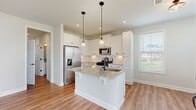Located at 2000 Harvest Pond Cir in Suwanee, GA, this well-appointed two-story home offers a clean, contemporary design with thoughtful finishes throughout. The main level features warm hardwood-style flooring that flows seamlessly from the open living area into the kitchen. The kitchen is a standout, showcasing crisp white shaker cabinetry, granite countertops with subtle veining, a central island with an undermount sink, classic subway tile backsplash, and a full suite of stainless steel appliances including a gas range, microwave, and French door refrigerator. Pendant lighting above the island adds a refined touch, while multiple windows invite ample natural light. The living area offers a back door leading to the exterior, enhancing connectivity to the outdoors. Bedrooms are generously sized, with plush carpeting, neutral tones, and windows that frame views of the surrounding neighborhood. Bathrooms are well-finished, featuring white cabinetry with matte black hardware, hardwood-style flooring, and a tiled walk-in shower enclosed by a glass door. The home's consistent neutral palette, modern fixtures, and quality finishes create a bright, move-in-ready environment suitable for a variety of lifestyles.