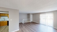 Located at 2505 Fox Harbour Dr in Indianapolis, IN, this multi-level space offers a clean, functional layout with a neutral color palette throughout. The upper level features a bright, open living area with wood-style luxury vinyl plank flooring, textured ceilings, and a sliding glass door framed by vertical blinds that floods the room with natural light and provides outdoor views. A white-railed staircase landing connects the levels, adding a structural focal point to the space.

The kitchen is equipped with warm oak cabinetry, white countertops, and stainless steel appliances including a refrigerator and range, complemented by a black dishwasher. A skylight overhead provides additional natural illumination, making the kitchen feel open and inviting. The flooring continues the wood-style LVP found throughout the main living areas.

The bedrooms are finished with plush carpeting and neutral-toned walls, offering a comfortable and quiet environment. Each room includes standard closet access and windows for natural light. The bathroom features a full tub-shower combination with a curved curtain rod, LVP flooring, and clean white fixtures, maintaining the space's consistent, understated aesthetic throughout.