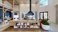 Located at 536 W Tremont Ave in Charlotte's vibrant Dilworth neighborhood, this expansive single-floor amenity space blends modern design with warm, residential character across a generously sized open-plan layout. Soaring double-height ceilings anchored by exposed light wood timber framing define the architectural identity of the space, while polished concrete floors flow seamlessly throughout, unifying the distinct zones within.

At the heart of the space, a dramatic suspended black metal fireplace serves as a bold focal point, surrounded by plush leather and upholstered sectional seating. Multiple lounge areas branch off from the central hub, each defined by deep navy accent walls, curated artwork, and a mix of textured furnishings that create intimate conversation nooks. A co-working area features a live-edge communal table beneath oversized pendant lighting, complemented by a coffee station and built-in cabinetry with wood paneling.

A bright dining area benefits from floor-to-ceiling steel-framed windows that flood the space with natural light and offer views of an outdoor pool. The full catering kitchen is outfitted with a long concrete-topped island, bar seating, subway tile backsplash, and stylish pendant fixtures. Throughout, lush greenery, layered textiles, and thoughtful lighting contribute to a sophisticated yet welcoming ambiance.