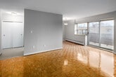 Located at 6 24th Street in Toronto's Mimico neighbourhood, this two-bedroom, one-bathroom unit offers a practical and well-organized layout across a single floor. Warm parquet flooring is a consistent design element throughout the living areas and bedrooms, lending a classic character to the interior.

The living room is the largest shared space, featuring a full-height sliding glass door that opens to an outdoor area and allows substantial natural light to fill the room. Neutral grey walls complement the light wood flooring and create a clean, versatile backdrop.

The galley-style kitchen is efficiently designed with white cabinetry extending to the ceiling, grey subway tile backsplash, light tile flooring, stainless steel appliances including a refrigerator and electric range, and a double undermount sink with ample counter space along both sides.

The generously sized primary bedroom offers a closet with double doors and connects through the hallway to the second bedroom, which is a comfortable secondary space also finished with parquet flooring. Both rooms feature neutral walls and clear sightlines.

The bathroom includes a full soaker tub with a shower, surrounded by large-format beige tile, providing a clean and functional finish. A hallway connects all rooms and leads to the unit's entry door.