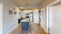 This 2-bedroom, 2-bathroom residence at 90 New St in New Brunswick, NJ offers a well-designed, single-floor layout with modern finishes throughout. The kitchen is a standout feature, equipped with stainless steel appliances including a refrigerator, range, microwave, and dishwasher. Crisp white upper cabinetry is complemented by navy lower cabinets, and a movable island with a white countertop provides additional prep space and casual seating. Light wood-style flooring runs through the kitchen and main living areas, adding warmth to the contemporary aesthetic. A convenient in-unit stacked washer and dryer is tucked behind louvered doors just off the kitchen. Both bedrooms are carpeted and feature windows that allow natural light to filter in, offering views of the surrounding cityscape. Each bedroom includes ceiling fans for added comfort. The two bathrooms mirror the unit's modern style, featuring floating dark-toned vanities with white countertops, large framed mirrors, wood-style flooring, and shower-tub combinations. Neutral, warm-toned walls throughout the unit create a cohesive and inviting ambiance, making this a functional and stylish home in the heart of New Brunswick.