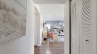 Located in Largo, Florida, this single-floor, two-bedroom, two-bathroom residence offers a well-designed layout with a comfortable and cohesive aesthetic throughout. The open living and dining area is anchored by wood-look flooring, a textured ceiling, and a distinctive blue accent wall that adds depth to the space. Large vertical blinds filter natural light while providing access to a screened patio, which frames serene views of mature trees and manicured green landscaping.

The kitchen features white cabinetry, dark countertops, and black appliances, including a refrigerator and electric range, with ample cabinet and counter space arranged in a functional galley-style configuration.

The primary bedroom is a comfortably sized retreat with wood-look flooring, a natural light-filled window, and a built-in closet with louvered doors. The second bedroom also offers its own window and closet storage. A dedicated walk-in closet with wire shelving provides additional storage capacity.

Both bathrooms are finished with white vanity cabinetry, stone-toned countertops, large mirrors, and wood-look flooring. One bathroom includes a tub-shower combination with tile surround, while the other features a shower. Hallways connect the spaces efficiently, contributing to the overall practical flow of the floor plan.