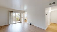 Located in Fremont, CA (94536), this single-floor unit offers a bright, clean, and well-organized layout. The living area is finished with light wood-style flooring and crisp white walls, creating an open and airy atmosphere. Sliding glass doors flood the space with natural light and provide direct access to a private patio with greenery and a stone perimeter wall, seamlessly connecting indoor and outdoor living.

The galley-style kitchen is efficiently designed with white cabinetry, granite-look countertops, white appliances including a range and dishwasher, and a stainless steel sink. A window at the end of the kitchen looks out to a small dining nook, which features a ceiling fan and room for a bistro-style table.

The bedrooms are carpeted in a neutral gray tone and receive natural light through windows fitted with vertical blinds. One bedroom includes an adjoining door that leads to an additional room or closet space. The layout provides a comfortable sense of privacy and separation between living and sleeping areas.

Two bathrooms serve the unit, both finished with light wood-style flooring and white cabinetry topped with stone-look counters. One bathroom features a tub/shower combination, while the other is appointed as a more compact full bath. The overall design throughout is clean, neutral, and move-in ready.