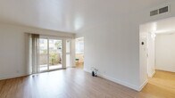 Located in Fremont, CA (94536), this single-floor unit offers a bright, clean, and well-organized layout. The living area is finished with light wood-style flooring and crisp white walls, creating an open and airy atmosphere. Sliding glass doors flood the space with natural light and provide direct access to a private patio with greenery and a stone perimeter wall, seamlessly connecting indoor and outdoor living.

The galley-style kitchen is efficiently designed with white cabinetry, granite-look countertops, white appliances including a range and dishwasher, and a stainless steel sink. A window at the end of the kitchen looks out to a small dining nook, which features a ceiling fan and room for a bistro-style table.

The bedrooms are carpeted in a neutral gray tone and receive natural light through windows fitted with vertical blinds. One bedroom includes an adjoining door that leads to an additional room or closet space. The layout provides a comfortable sense of privacy and separation between living and sleeping areas.

Two bathrooms serve the unit, both finished with light wood-style flooring and white cabinetry topped with stone-look counters. One bathroom features a tub/shower combination, while the other is appointed as a more compact full bath. The overall design throughout is clean, neutral, and move-in ready.
