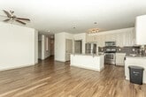 Located at 675 Lafayette Ave in Fayetteville, Georgia, this single-story space offers a thoughtfully designed interior with consistent, modern finishes throughout. Rich hardwood-style flooring runs through the main living areas, complementing the neutral white walls and creating a clean, contemporary aesthetic.

The kitchen is a standout feature, equipped with white shaker-style cabinetry, granite countertops, a mosaic tile backsplash, and a full suite of stainless steel appliances including a refrigerator, range, microwave, and dishwasher. A central island provides additional workspace and visual appeal. Natural light fills the adjacent dining and living area through a bank of large windows fitted with blinds, offering views of surrounding greenery.

A long entry hallway connects the main living spaces to the private areas of the unit. The bathroom features granite countertops on gray cabinetry, hardwood-style flooring, and a tub-shower combination with classic white subway tile surround. A spacious walk-in closet with wire shelving provides ample storage. A dedicated laundry room includes a full-size washer and dryer with overhead shelving. Ceiling fans in the main living areas add comfort and functionality.