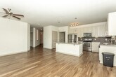 Located at 675 Lafayette Ave in Fayetteville, Georgia, this single-story space offers a thoughtfully designed interior with consistent, modern finishes throughout. Rich hardwood-style flooring runs through the main living areas, complementing the neutral white walls and creating a clean, contemporary aesthetic.

The kitchen is a standout feature, equipped with white shaker-style cabinetry, granite countertops, a mosaic tile backsplash, and a full suite of stainless steel appliances including a refrigerator, range, microwave, and dishwasher. A central island provides additional workspace and visual appeal. Natural light fills the adjacent dining and living area through a bank of large windows fitted with blinds, offering views of surrounding greenery.

A long entry hallway connects the main living spaces to the private areas of the unit. The bathroom features granite countertops on gray cabinetry, hardwood-style flooring, and a tub-shower combination with classic white subway tile surround. A spacious walk-in closet with wire shelving provides ample storage. A dedicated laundry room includes a full-size washer and dryer with overhead shelving. Ceiling fans in the main living areas add comfort and functionality.