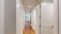 Located in the heart of New Orleans' iconic French Quarter at 221 Chartres Street, this two-bedroom, two-bathroom residence combines modern design with a well-planned layout across a single floor. Warm-toned hardwood flooring flows throughout the living areas, bedrooms, and hallway, lending a cohesive and inviting character to the space.

The kitchen serves as a central showpiece, featuring a large white quartz waterfall island with an undermount sink, sleek gray shaker cabinetry extending to the ceiling, a herringbone tile backsplash, stainless steel appliances including a gas range and refrigerator, and globe pendant lights that add a contemporary flair. The tall ceilings and track lighting enhance the open, airy atmosphere.

The primary bedroom offers a comfortable footprint with a double-door closet and track lighting, while the second bedroom includes a narrow window that brings in natural light. A dedicated closet provides additional storage.

The two bathrooms are distinctly appointed. One features a glass-enclosed walk-in shower with large-format marble-style tile and chrome fixtures, while the second includes a full soaking tub framed by classic white subway tile and a sliding glass door. Both are finished with neutral floor tile for a clean, modern aesthetic.

A well-lit hallway connects the bedrooms and bathrooms, completing this efficiently designed and thoughtfully finished residence.