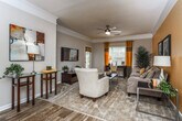This single-floor residence at 402 Carrington Park in Jonesboro, Georgia, offers a thoughtfully designed layout that balances comfort and functionality. The living room serves as the heart of the home, featuring crown molding, a textured ceiling with a ceiling fan, and soft carpet underfoot. Warm neutral and accent wall tones create an inviting atmosphere, with windows dressed in layered curtains allowing ample natural light.

The dining area adjoins the living space and features wood-look flooring, crown molding, and neutral walls—an elegant yet understated setting for everyday meals or entertaining. The galley-style kitchen is well-equipped with white cabinetry, dark countertops, wood-look flooring, and black appliances including a refrigerator and electric range, all framed by crown molding detail.

The bedrooms offer carpeted floors and generous natural light. The primary bedroom includes a bay window arrangement with floor-length drapes, while secondary bedrooms feature similarly styled windows. Two full bathrooms provide white vanity cabinetry, wood-look tile flooring, and tub-shower combinations. A dedicated laundry room accommodates a full-size washer and dryer, adding everyday convenience to this well-rounded home.