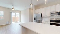 Located in Cypress, TX, this single-story, 3-bedroom, 2-bathroom home offers a clean, modern aesthetic with an open-concept floor plan that maximizes both functionality and flow. Light wood-tone flooring runs throughout, complemented by crisp white walls and an abundance of natural light from multiple windows.

The kitchen is a standout feature, showcasing white shaker cabinetry, a subway tile backsplash, stainless steel appliances — including a French door refrigerator, range, microwave, and dishwasher — and a large central island with a gleaming white countertop. Pendant lighting above the island adds a polished finishing touch. The kitchen opens seamlessly into the living room, which features a ceiling fan and sliding glass doors that lead to a fenced backyard.

The primary bedroom is a comfortable retreat with natural light and its own access to a well-appointed bathroom featuring a dual-sink vanity with white cabinetry, quartz countertops, and framed mirrors with chrome fixtures. Two additional bedrooms are bright and well-sized, each with wood flooring and window treatments. Spacious closets, including a walk-in with full-length rods, provide ample storage. A dedicated laundry space with a full-size washer and dryer completes this thoughtfully designed home.