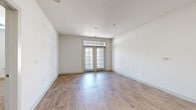 Located at 3201 Windshire Ln in Charlotte, NC, this well-designed two-bedroom, two-bathroom residence offers a clean, modern aesthetic throughout its single-floor layout. The open living room is bright and airy, featuring wood-look plank flooring and a set of French doors topped with a transom window that ushers in natural light. The kitchen is a standout, showcasing a large island with granite countertops and an undermount sink, rich dark cabinetry, and stainless steel appliances including a French door refrigerator. Both bedrooms are carpeted for comfort, each featuring windows that provide natural light and outdoor views. The primary bedroom includes a ceiling fan and generous closet space. The primary bathroom offers a walk-in shower with a glass sliding door, dark wood vanity, and wood-look flooring, while the secondary bathroom features a tiled tub-shower combo and a matching dark wood vanity with a white countertop. A dedicated laundry room houses a full-size side-by-side washer and dryer with overhead shelving for added storage. The hallway connects all rooms efficiently, and the neutral color palette throughout creates a cohesive, move-in-ready feel.