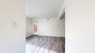 This single-story, 3-bedroom, 2-bathroom home offers a thoughtfully organized layout with a clean, neutral palette that creates a bright and airy atmosphere throughout. The living room features light wood-style flooring, a textured ceiling, and a glazed exterior door that allows natural light to flow into the space. A vaulted ceiling detail adds architectural interest and a sense of openness to the living area. The kitchen is positioned adjacent to the living space and features a pass-through counter, white cabinetry, a light countertop surface, and black appliances including a refrigerator and range, all complemented by wood-style flooring. The three bedrooms are finished with soft carpeting and white walls, each offering generous closet storage. The primary bedroom includes a walk-in closet with built-in shelving, while additional bedrooms feature bi-fold door closets with hanging rods. Bedrooms are brightened by windows with horizontal blinds offering outdoor views. The two bathrooms are finished with light wood-style flooring, white fixtures, and clean, minimal design. Two hallways provide convenient connectivity throughout the home. The overall ambiance is functional and move-in ready, with consistent neutral finishes that offer a versatile foundation for any interior style.