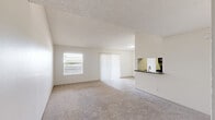 Located along South Interstate 35 in Austin, TX, this one-bedroom, one-bathroom unit offers a practical and well-organized single-floor layout. The open living area is finished with neutral-toned carpet and features a large sliding glass door with vertical blinds alongside a side window, allowing natural light to fill the space. A textured ceiling and clean white walls contribute to a bright, airy atmosphere throughout.

The galley-style kitchen is accessible directly from the living area via a pass-through counter with dark countertops. The kitchen features light wood-look vinyl flooring, gray cabinetry on both sides, dark appliances including a refrigerator and range, and a dedicated closet, maximizing storage and functionality in a compact footprint.

The bedroom is a comfortable size, featuring plush carpet, a window for natural light, a textured ceiling, and easy access to the hallway and closet. The full bathroom includes a tiled tub and shower combination with a curved curtain rod, wood-look flooring, and neutral-toned walls, providing a clean and utilitarian design.

A connecting hallway ties all rooms together efficiently, completing this straightforward and well-maintained layout suited for single occupancy or couples in Austin's South Congress corridor.