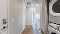 This thoughtfully designed single-floor residence combines contemporary finishes with a functional, open layout. The kitchen serves as a central hub, featuring white shaker cabinetry, a striking herringbone tile backsplash, stainless steel appliances including a French door refrigerator, electric range, and over-the-range microwave, along with a central island with bar seating and pendant lighting overhead. Rich hardwood flooring flows throughout the main living areas, anchoring the space with warmth and continuity.

The living area is bathed in natural light through floor-to-ceiling windows that frame sweeping panoramic views of the surrounding cityscape and distant mountains, creating a bright and airy atmosphere. The space accommodates comfortable seating arrangements ideal for both relaxing and entertaining.

Two well-appointed bedrooms offer carpeted flooring and restful retreats, with the primary bedroom featuring large windows that capture the same impressive views. The primary bathroom is finished with a dual-sink vanity topped in white quartz, white shaker cabinetry with brushed nickel hardware, and a large mirror with overhead lighting. A second full bathroom provides a single-sink vanity with ample storage and hardwood-style flooring. Clean, white-painted walls and recessed lighting throughout the hallways contribute to the space's bright, modern ambiance.