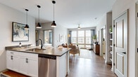 Located at 500 Congaree Rd in Greenville, SC, this well-appointed 2-bedroom, 3-bathroom residence offers a thoughtfully designed single-floor layout. The open-concept living and kitchen area serves as the heart of the home, where hardwood-style flooring flows seamlessly throughout. The kitchen is outfitted with white shaker cabinetry, subway tile backsplash, dark quartz countertops, stainless steel appliances, and a generous island with pendant lighting — ideal for both cooking and casual dining. The living room is bathed in natural light from large windows that frame outdoor views, and features a ceiling fan overhead. Both bedrooms are comfortably sized, carpeted, and filled with natural light from expansive windows with draping curtains. The spacious primary bedroom includes a walk-in closet with built-in wire shelving. The three bathrooms are finished with white subway tile, dark quartz vanity counters, white cabinetry, and matte black fixtures — one bath features a soaking tub, while another offers a glass-enclosed shower. Two closets provide ample storage throughout the residence. The overall ambiance is modern and cohesive, combining clean finishes with a warm, inviting palette.
