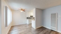 This single-floor residence offers a thoughtfully designed layout with clean, modern finishes throughout. The living area is bright and open, featuring light wood-tone flooring, a ceiling fan with light fixture, and a textured ceiling. Sliding glass doors lead to an outdoor balcony area, allowing natural light to fill the space, while vertical blinds and additional windows further enhance the airy atmosphere. A wall-mounted HVAC unit ensures year-round comfort.

The galley-style kitchen is efficiently laid out with crisp white cabinetry, sleek silver hardware, and light-toned countertops. A striking mosaic tile backsplash adds visual interest, and stainless steel appliances — including a gas range and refrigerator — complete the functional setup. The kitchen opens toward the living area via a pass-through counter, creating a connected feel.

The bedroom is a serene retreat with soft gray walls, wood-tone flooring, and a textured ceiling. It includes a dedicated walk-in closet with built-in shelving, offering ample storage. The full bathroom is finished in bright white tones, featuring a single-sink vanity with white cabinetry, a framed mirror, and a full-size tub and shower combination. Wood-tone flooring ties the bathroom's aesthetic to the rest of the residence seamlessly.