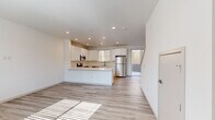 Located on Cedar Pine Drive in Longmont, Colorado, this two-story home offers a well-designed layout across two floors. The main level features an open-concept living and kitchen area bathed in natural light from large windows and sliding glass door access to the outdoors. The kitchen is outfitted with crisp white shaker cabinetry, a full suite of stainless steel appliances including a refrigerator, range, microwave, and dishwasher, and a peninsula with a clean white countertop that defines the space. Light wood-look flooring runs throughout the main level, enhancing the bright and airy feel. A half bathroom on this floor adds everyday convenience. Upstairs, the primary bedroom features plush carpeting, a ceiling fan, and an en suite bathroom with a dual-sink white vanity, wood-look tile flooring, and a glass-enclosed walk-in shower. The second bedroom is equally well-lit, with large windows, light flooring, and a ceiling fan. A third full bathroom serves the upper floor. Recessed lighting is featured throughout, and the home's neutral white palette and modern finishes create a clean, cohesive atmosphere ideal for comfortable living.