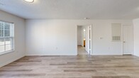 Located at 1923 Spring Garden St in Greensboro, NC, this single-floor, 3-bedroom, 2-bathroom residence offers a practical and well-organized layout. The combined kitchen and living area forms the heart of the home, with the kitchen featuring warm honey-toned cabinetry, white appliances including a refrigerator, electric range, microwave, and dishwasher, plus light-colored countertops and a sink. Light vinyl plank flooring runs throughout the main living spaces, lending a clean and cohesive look. The open living room is bright and neutral, with a textured ceiling and easy access to the kitchen. Each of the three bedrooms is carpeted for comfort, with two rooms showcasing ceiling fans and windows that bring in natural light and outdoor views. The primary bedroom offers a generous footprint with access to additional storage. Two full bathrooms serve the home, each equipped with a tub-shower combination, wood-toned vanity cabinetry, and updated light fixtures. Two closets provide added storage convenience throughout. The overall aesthetic is clean and move-in ready, with white walls, neutral finishes, and consistent flooring choices that create a bright, functional living environment.