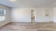 Located at 1923 Spring Garden St in Greensboro, NC, this single-floor, 3-bedroom, 2-bathroom residence offers a practical and well-organized layout. The combined kitchen and living area forms the heart of the home, with the kitchen featuring warm honey-toned cabinetry, white appliances including a refrigerator, electric range, microwave, and dishwasher, plus light-colored countertops and a sink. Light vinyl plank flooring runs throughout the main living spaces, lending a clean and cohesive look. The open living room is bright and neutral, with a textured ceiling and easy access to the kitchen. Each of the three bedrooms is carpeted for comfort, with two rooms showcasing ceiling fans and windows that bring in natural light and outdoor views. The primary bedroom offers a generous footprint with access to additional storage. Two full bathrooms serve the home, each equipped with a tub-shower combination, wood-toned vanity cabinetry, and updated light fixtures. Two closets provide added storage convenience throughout. The overall aesthetic is clean and move-in ready, with white walls, neutral finishes, and consistent flooring choices that create a bright, functional living environment.
