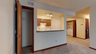 Located at 825 Crossing Court in Virginia Beach, Virginia, this single-floor residence offers a functional and well-organized layout suited for comfortable everyday living. The interior is finished with warm wood trim accents and neutral-toned carpeting throughout, creating a cohesive and inviting atmosphere.

At the heart of the home, the kitchen features a distinctive pass-through cutout that opens to the main living area, promoting an open and connected feel between spaces. The kitchen is equipped with warm wood cabinetry, an electric range, and overhead ventilation, with recessed lighting illuminating the workspace. The pass-through counter adds a casual dining or serving option while maintaining visual openness.

Adjacent to the kitchen, a spacious closet with a built-in rod and shelving provides ample storage. The in-unit laundry area is conveniently situated nearby, housing a full-size washer and dryer, adding to the home's practical appeal. The flooring transitions between carpeted living areas and hard-surface utility spaces, offering both comfort and durability where needed.

The single-story design ensures easy accessibility throughout, with each area flowing naturally into the next. The overall ambiance is clean, neutral, and move-in ready, making this Virginia Beach home a straightforward and efficient living space.