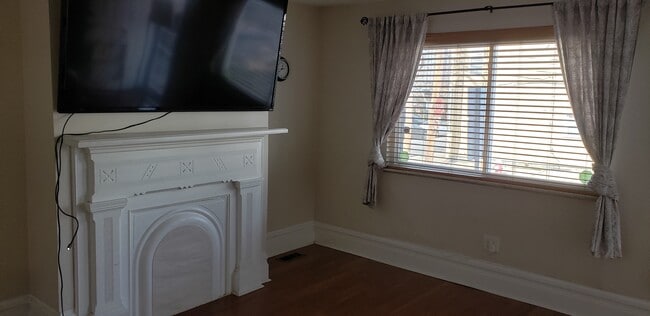 Living room window with plenty of natural light. 70" TV mounted to wall included with rental! - 1702 Sidney St