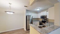 Located at 1907 Quaker Creek Dr in Mebane, North Carolina, this single-floor home offers a well-designed layout with functional living spaces throughout. The kitchen is a standout feature, equipped with stainless steel appliances including a refrigerator, electric range, and over-the-range microwave. Crisp white cabinetry provides ample storage, while granite-look countertops and a peninsula with a double stainless steel sink add both style and practicality. Wood-look vinyl plank flooring runs through the kitchen and main living areas, lending a clean and cohesive aesthetic. The open living area is bright and versatile, with neutral walls and textured ceilings. Bedrooms are carpeted for comfort and feature windows that allow natural light to filter in, with some rooms offering multiple windows for enhanced brightness. A walk-in closet with wire shelving provides generous storage in the primary bedroom. The bathrooms include full tub/shower combos with curved curtain rods, and at least one bathroom features a white vanity with a framed mirror and wood-look flooring. A hallway connects the main areas to the bedrooms, creating a practical and organized flow throughout this comfortable single-story home.